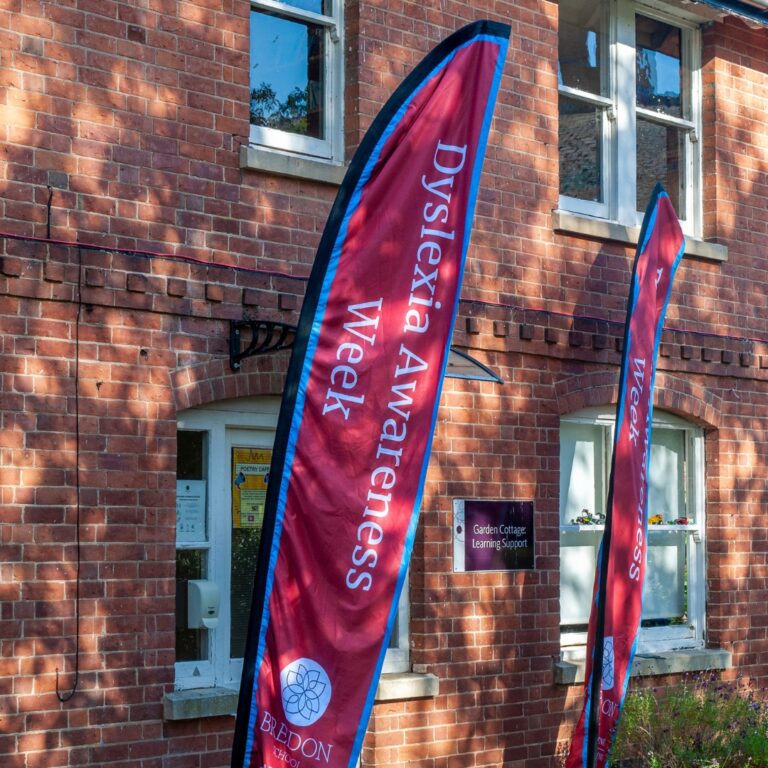 Brick building with two red banners reading 'Dyslexia Awareness Week' outside Bredon School.